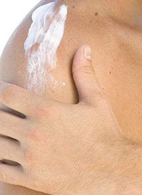 person applying cream on their shoulder